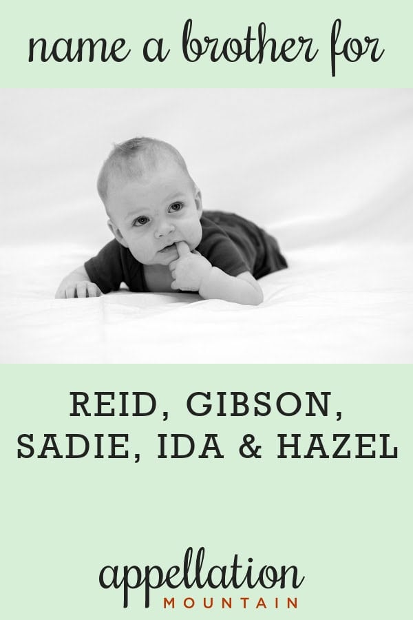 baby boy with light hair and dark onesie on his stomach on white blanket; polished boy names like Reid, Gibson, Sadie, Ida, and Hazel