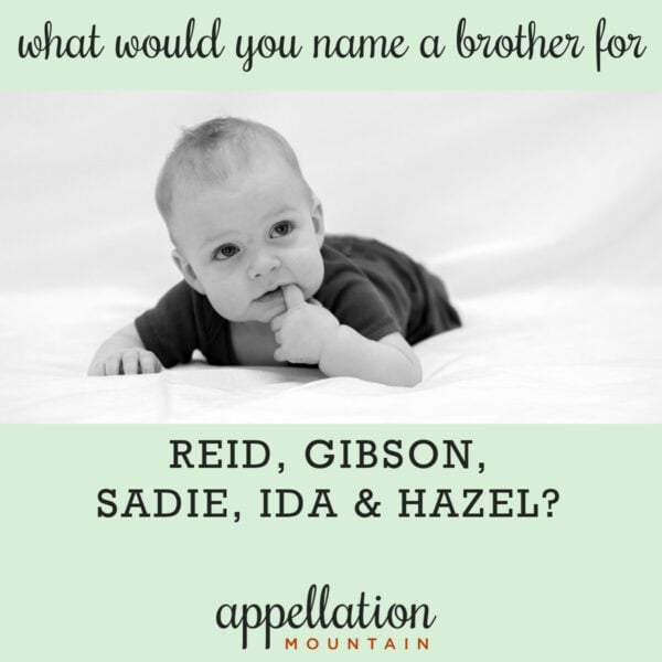 baby boy with light hair and dark onesie on his stomach on white blanket; polished boy names like Reid, Gibson, Sadie, Ida, and Hazel
