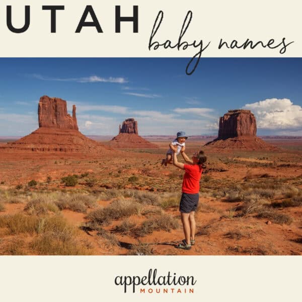 mom wearing red tee and shorts holding baby wearing blue hat up in her arms in a red rock canyon in Utah; Utah baby names