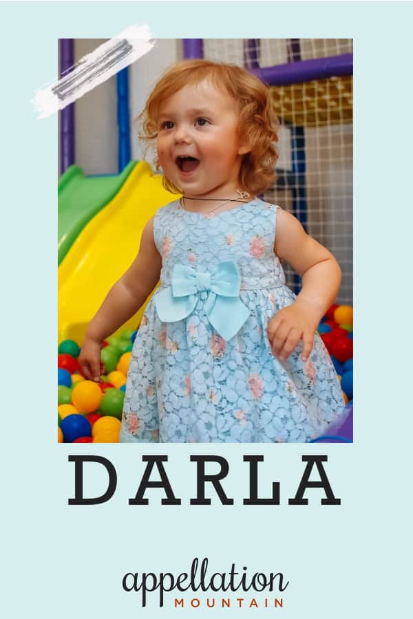 toddler girl with red curls wearing blue dress in indoor playground; baby name Darla