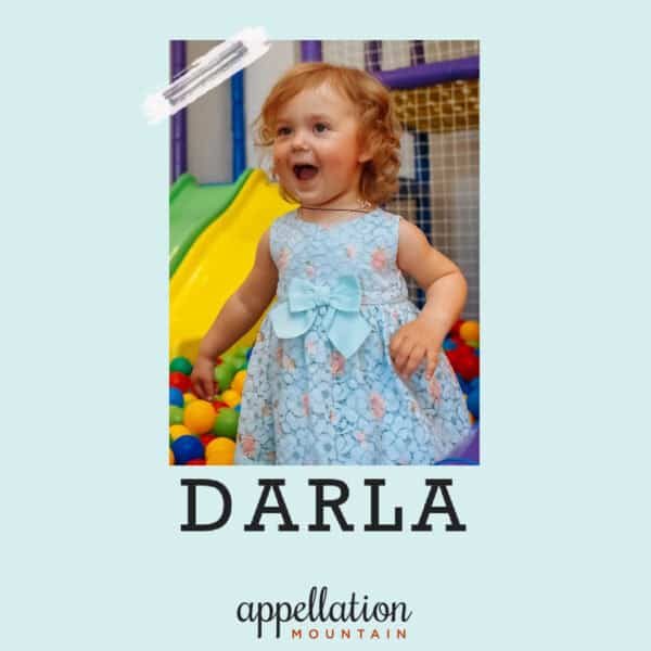toddler girl with red curls wearing blue dress in indoor playground; baby name Darla
