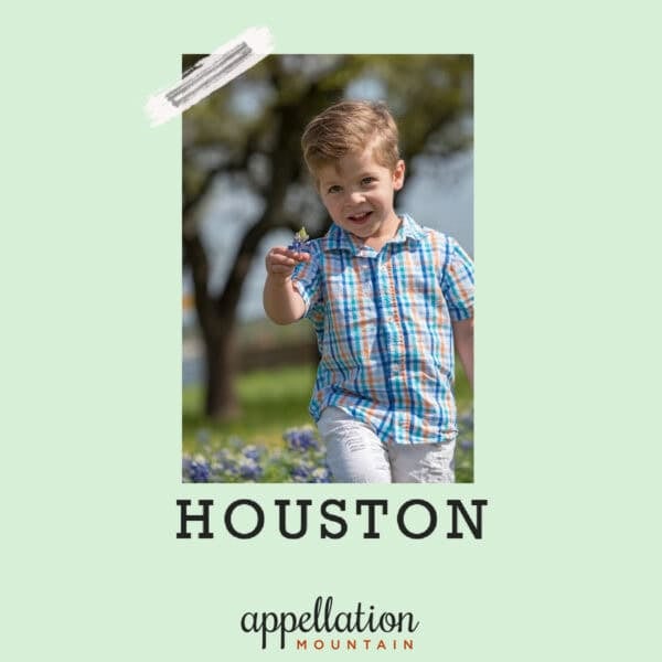 blonde boy child wearing blue plaid shirt, pointing toward camera while walking across field with tree in background; baby name Houston